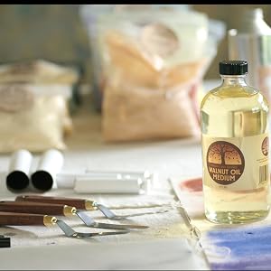 8oz bottle of walnut oil sitting on a table next to som empty paint tubes and pallet knives.