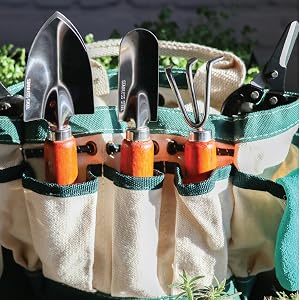 A toolbelt full of gardening tools including a trowel and weeding fork.