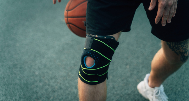 Man playing basketball wearing knee brace