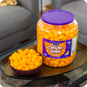 Utz Cheese Balls container and bowl on a tray table in a living room, creating a fun snack vibe.