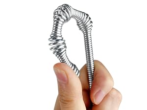 Flexible metallic spiral spring held between fingers, showing its coiled and bendable structure.