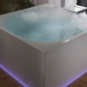 An Infinity tub with whirlpool features, steam, and fog with purple accent light