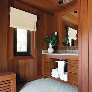 Walls made from redwood are shown in a bathroom with towels, a window, sink, and mirror