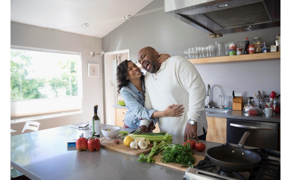 Middle age couple laughing while cooking a meal together