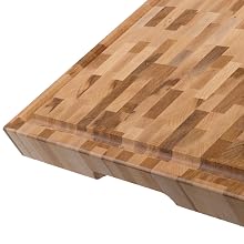 Close-up of a butcher block or wooden cutting board showing edge grain pattern with multiple wood strips joined together.