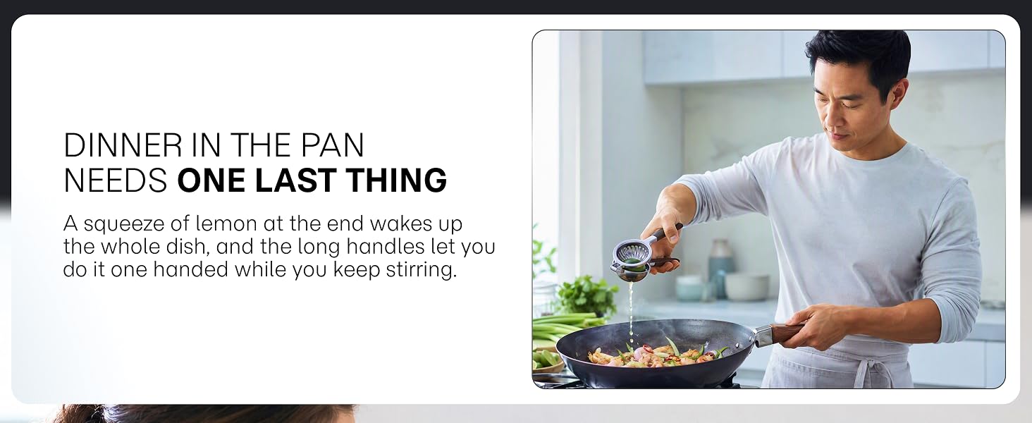 A man finishes a wok dish by squeezing lemon over it one handed with a metal citrus press.