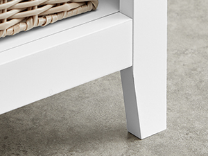 Corner of a white furniture piece, possibly a table or shelf, against a concrete or gray floor surface.