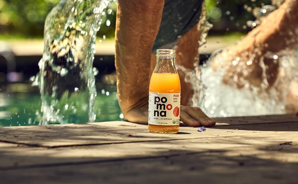 MAN STEPPING OUT OF POOL WITH BOTTLE OF POMONA ORGANIC APPLE JUICE