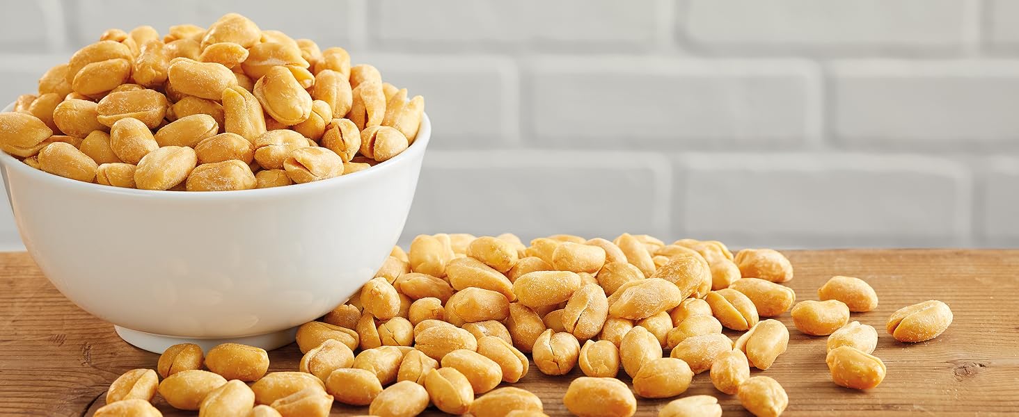 peanuts in bowl next to loose peanuts on a wood table top