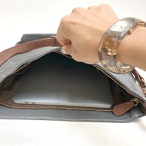 A hand holds open the MAIKA Crossbody bag to show the interior pocket.