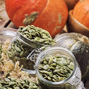 A picture of pumpkin kernels in jars with pumpkins in the background.