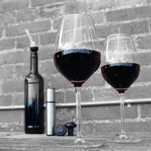 Two glasses of wine with the wine bottle, wine aerator and wine pump in the background