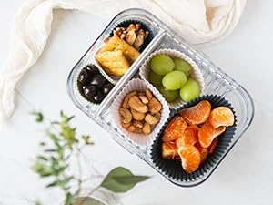 Silicone baking cups of various sizes in a lunch box sorting fruits, nuts, crackers