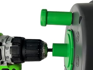 Close-up of green plastic connector or adapter being attached with black power drill, showing mechanical assembly process.