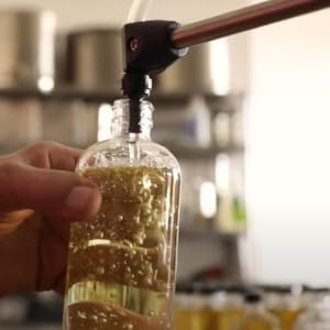 a hand holding a bottle being filled with walnut oil