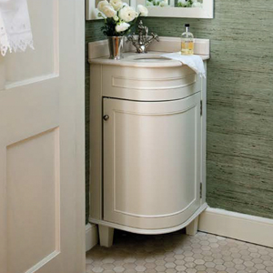 A small sink and cabinet is tucked neatly in a corner of a bathroom