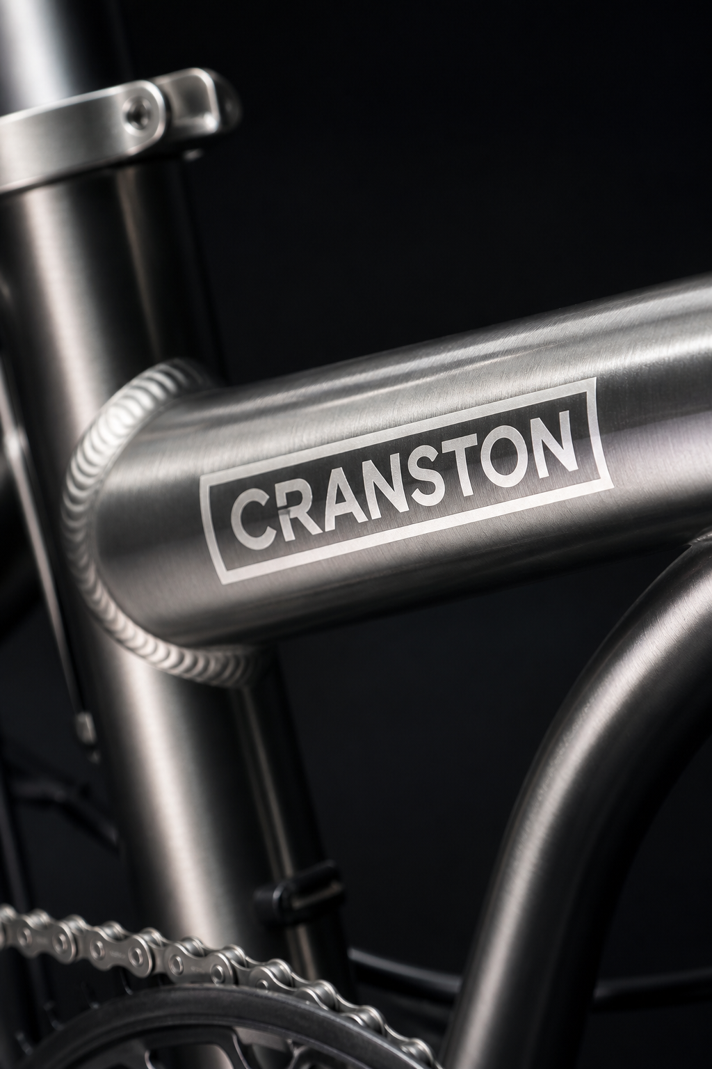 Extreme macro photograph of the silver CRANSTON aluminum bike frame, highlighting high-quality welding and branding