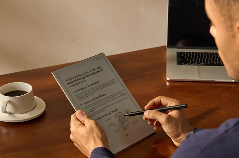 Using a stylus on a digital tablet at a desk.