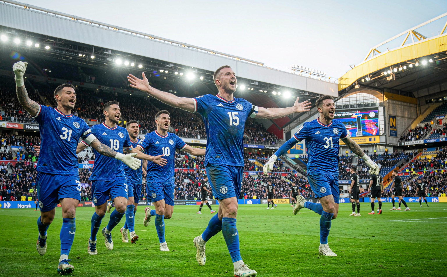 Manchester United 2026/27 away kit celebration after the 5-0 pre-season win over Rosenborg BK in Norway — five players in the royal blue away strip with red and white V-neck detailing