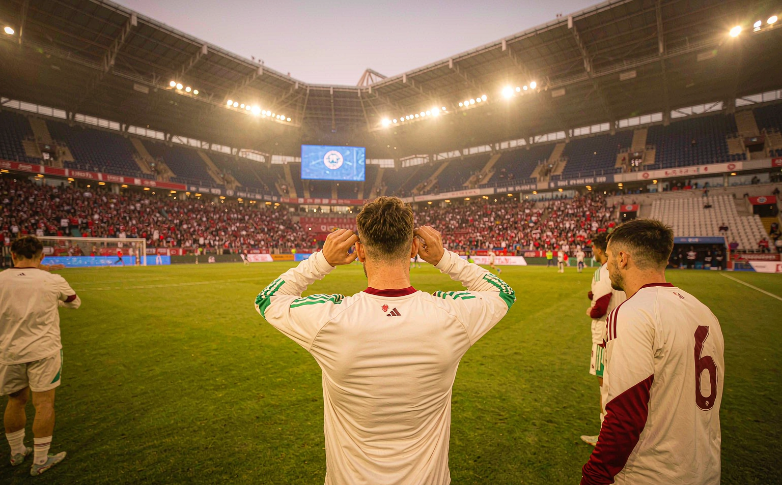 Manchester United 2026/27 third kit on-pitch debut at Stadion Wrocław — ivory base with maroon and green stripes, players saluting the crowd after the final pre-season friendly against AC Milan