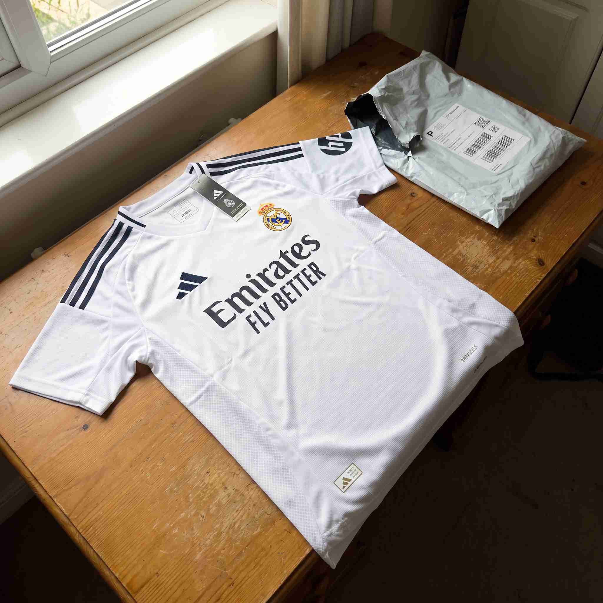 White home soccer kit unboxed with tags on bedroom hanger