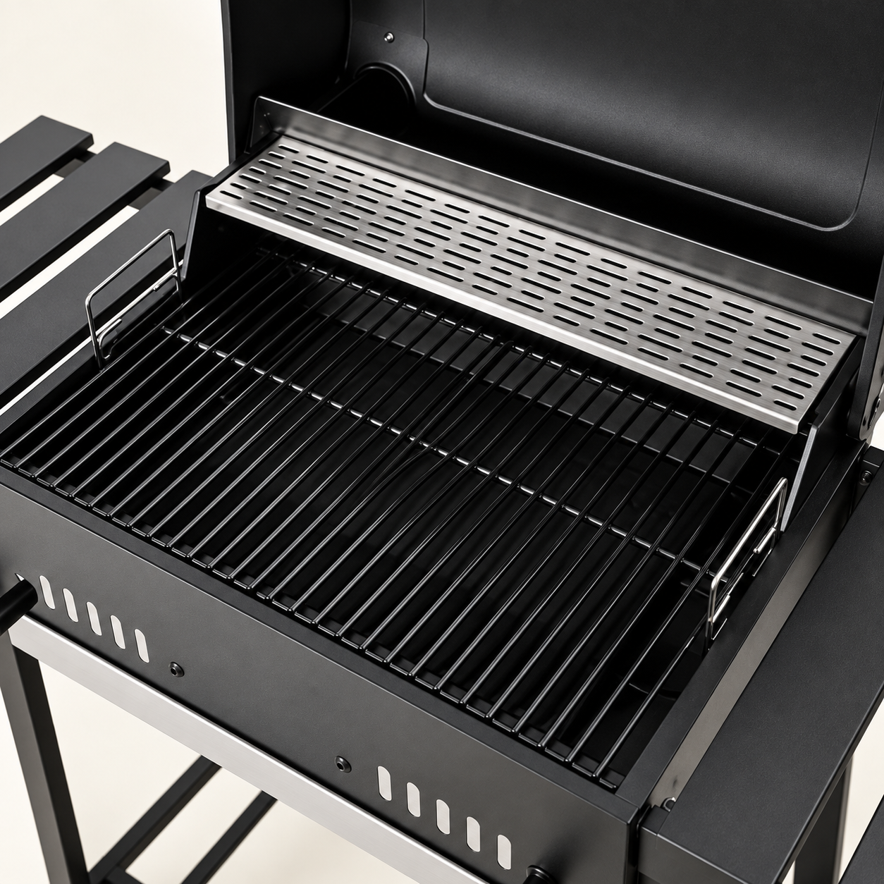 Open black metal table grill showing porcelain-enamel cooking grates and raised stainless warming rack