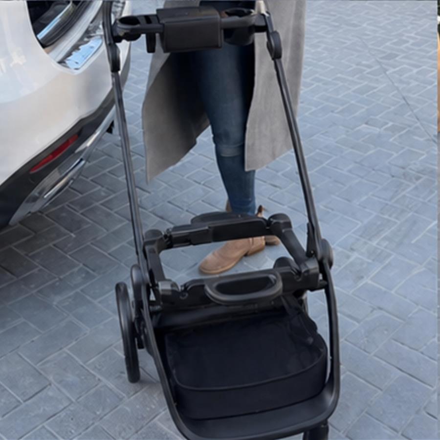 Empty stroller frame unfolded and waiting beside the open car boot