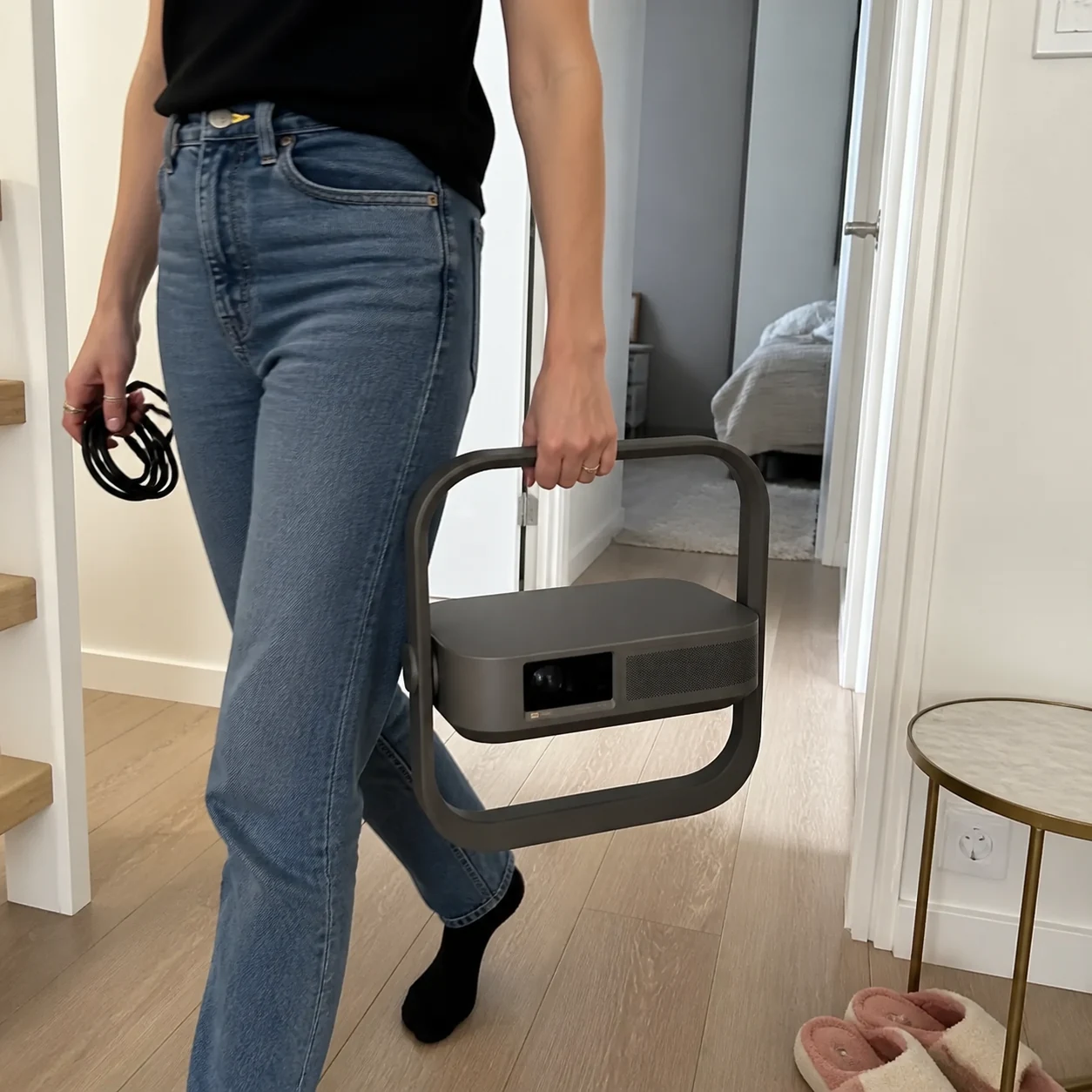 Woman carrying the projector by its square frame through a hallway