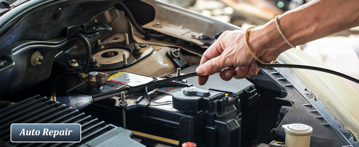 Mechanic's hand performing maintenance on car engine, holding tool over open engine compartment.