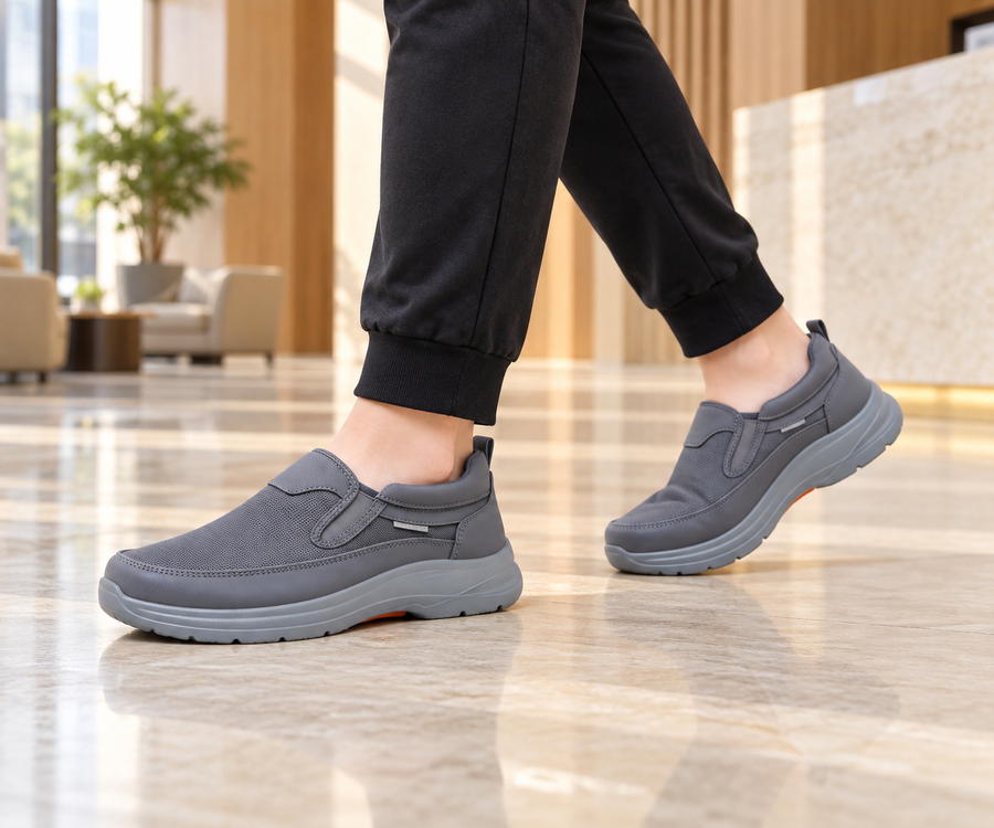 Grey mesh slip-on walking sneakers worn in a modern lobby
