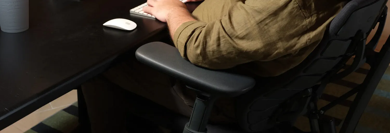 Chair armrest supporting a seated user's arm at a desk