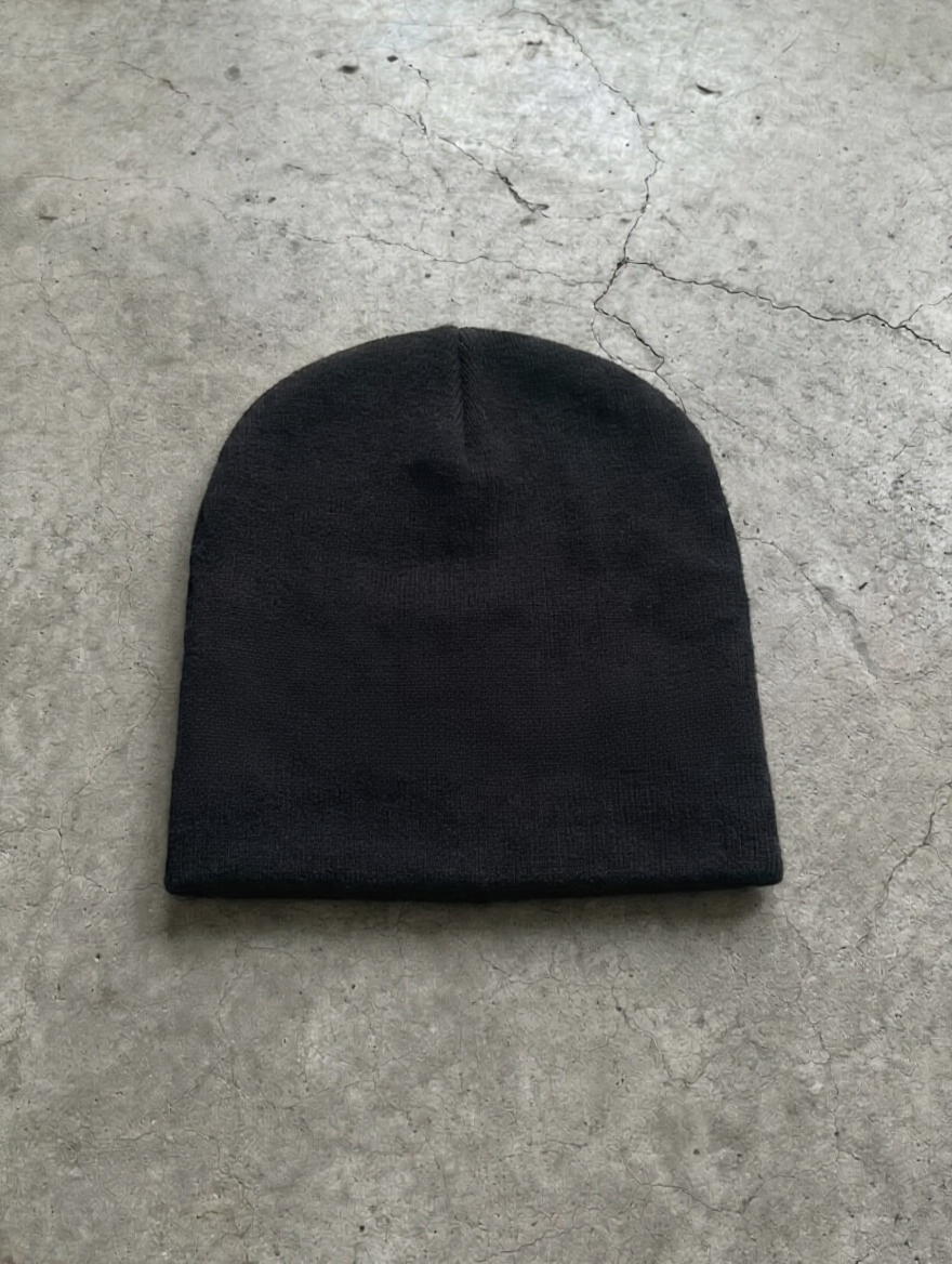 Black knitted cuffed beanie laying on the floor
