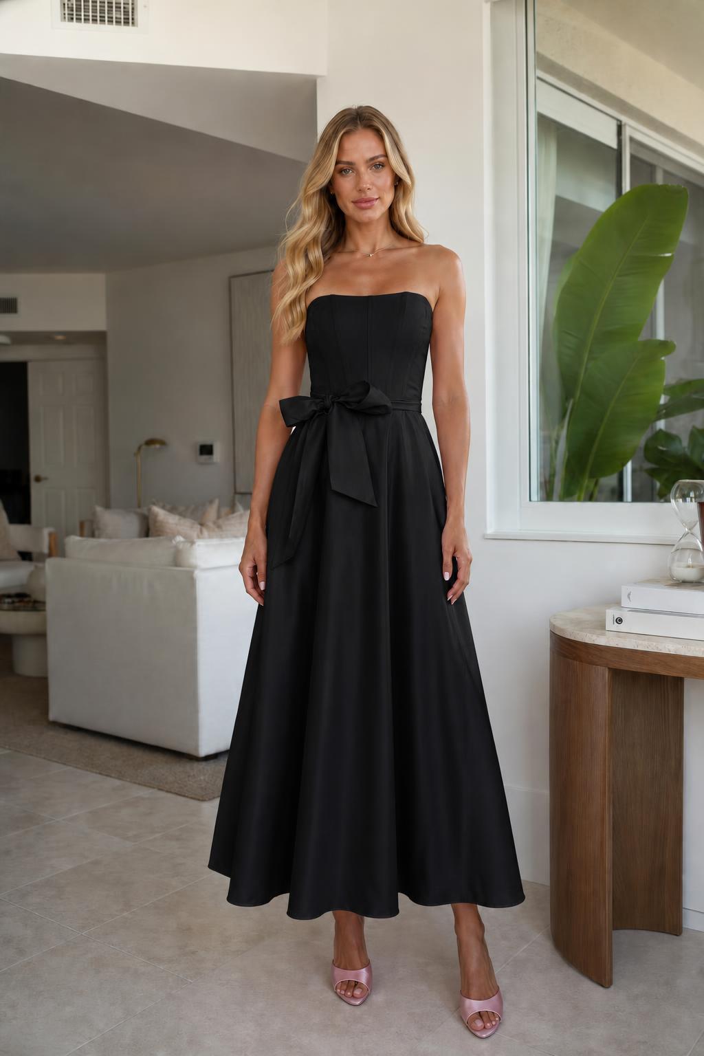 Model wearing black strapless bow waist midi dress