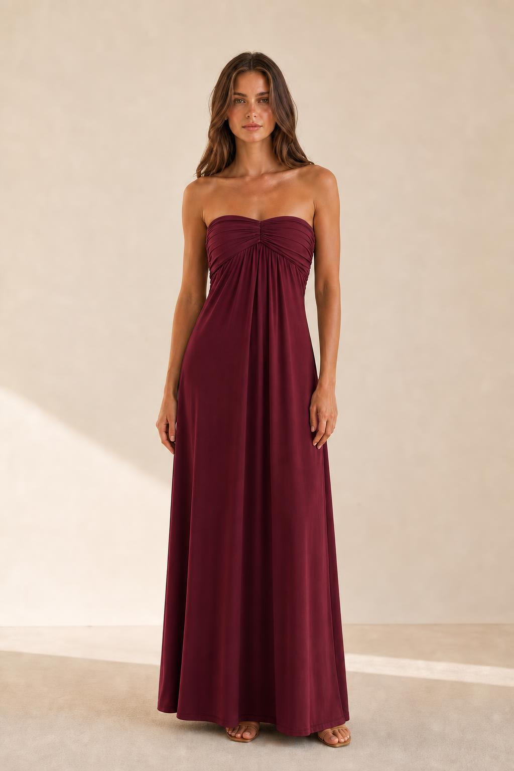 Woman wearing burgundy strapless ruched maxi dress front view