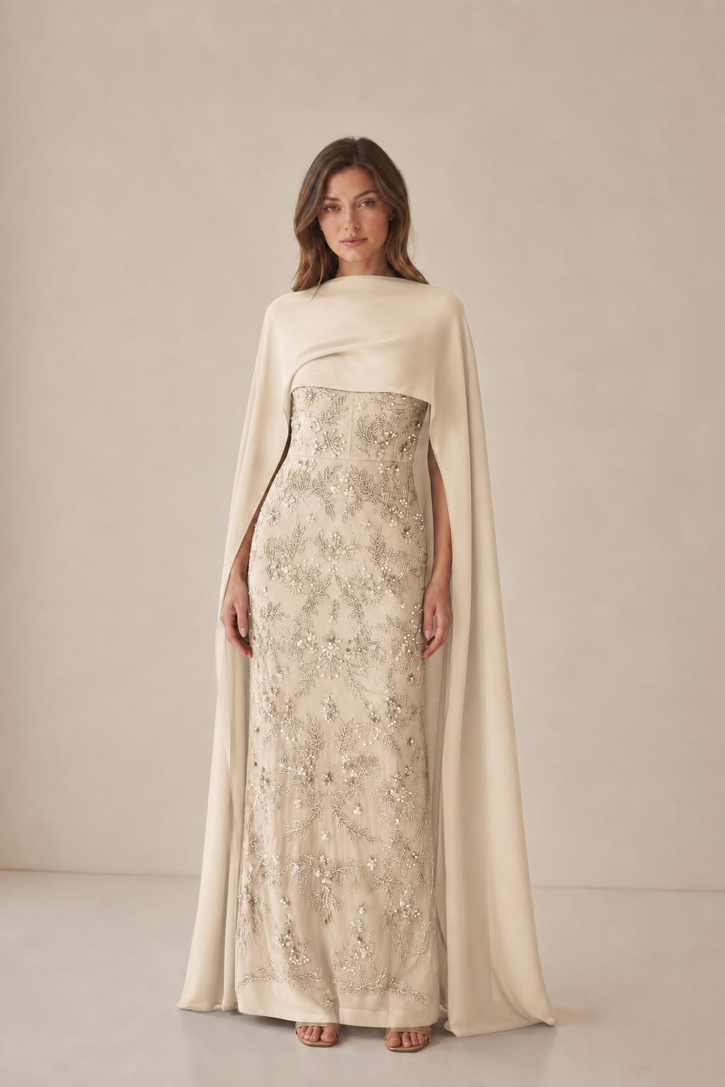 Model wearing champagne beaded dress with cape overlay