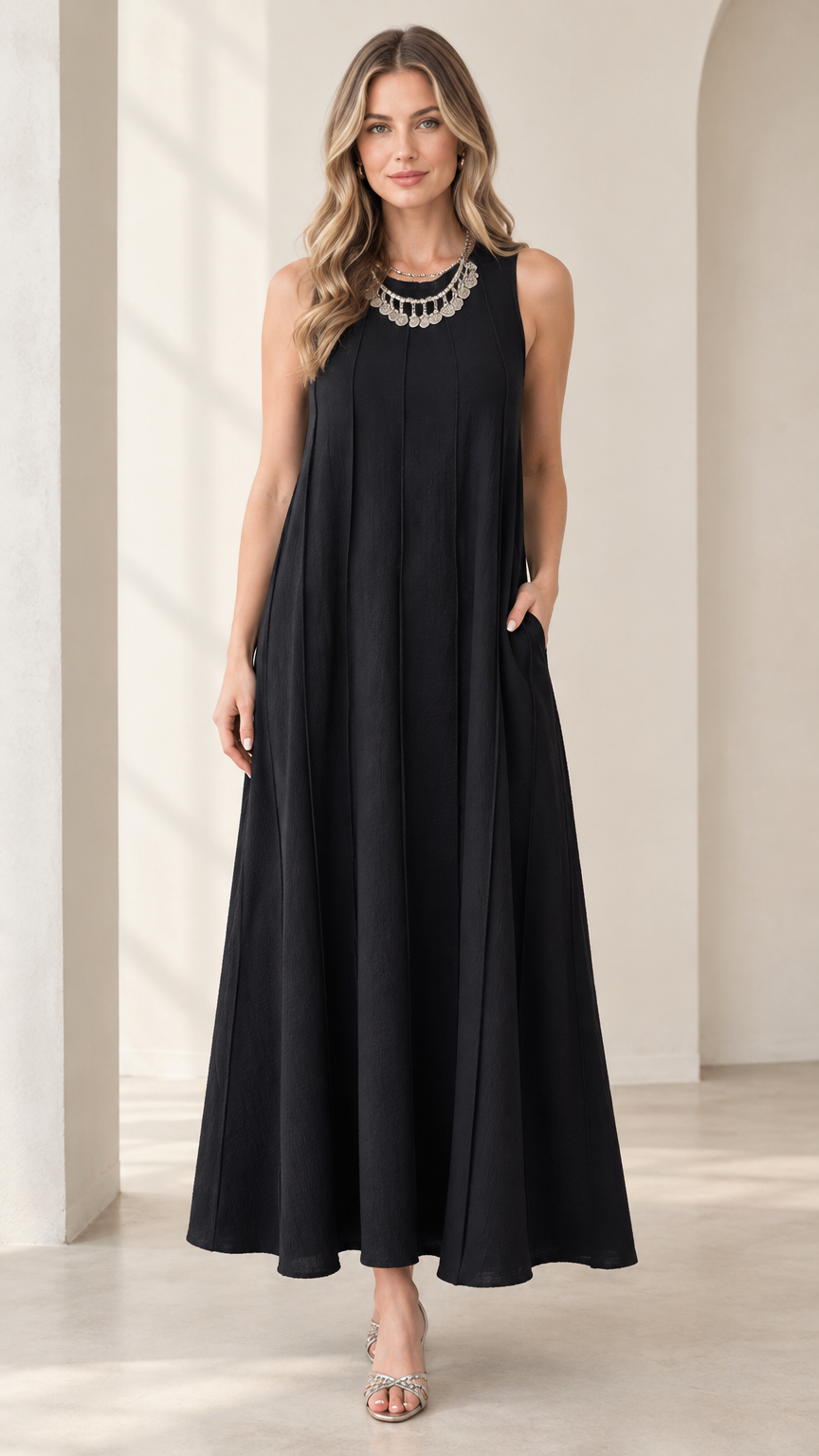 Front full-length view of woman wearing black sleeveless panel swing maxi dress with statement necklace