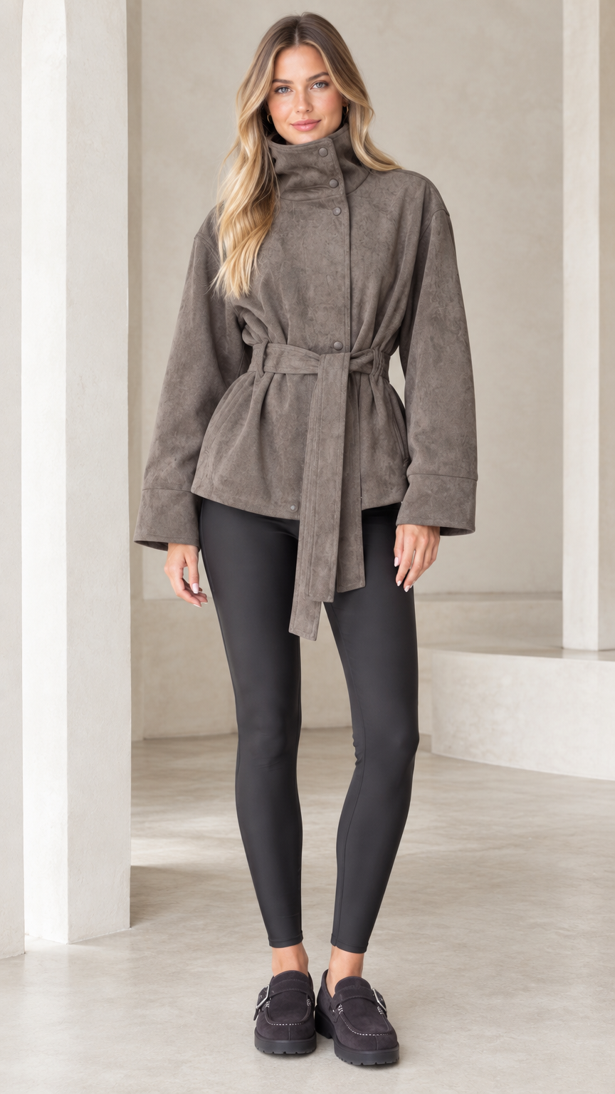 Front view of model wearing taupe high-neck belted faux suede jacket with black leggings