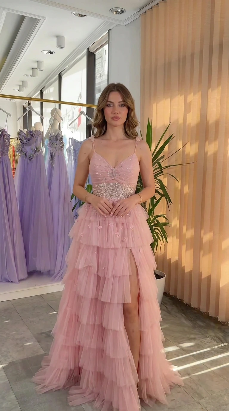Front full view of pink spaghetti strap tiered ruffle tulle evening gown with embellished waist and slit