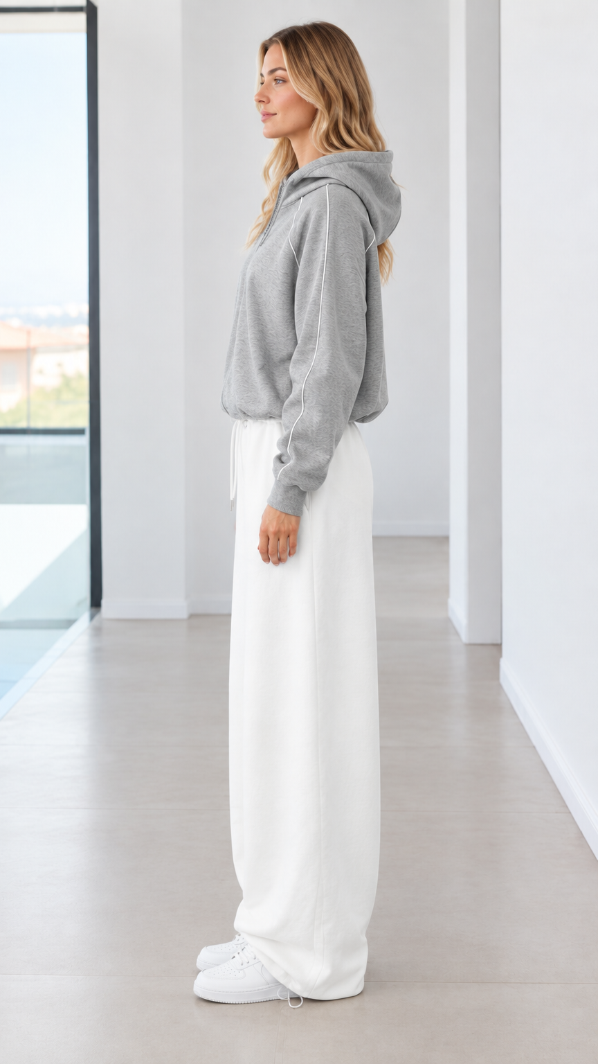 Side profile of model in heather grey hooded sweatshirt and white wide-leg sweatpants