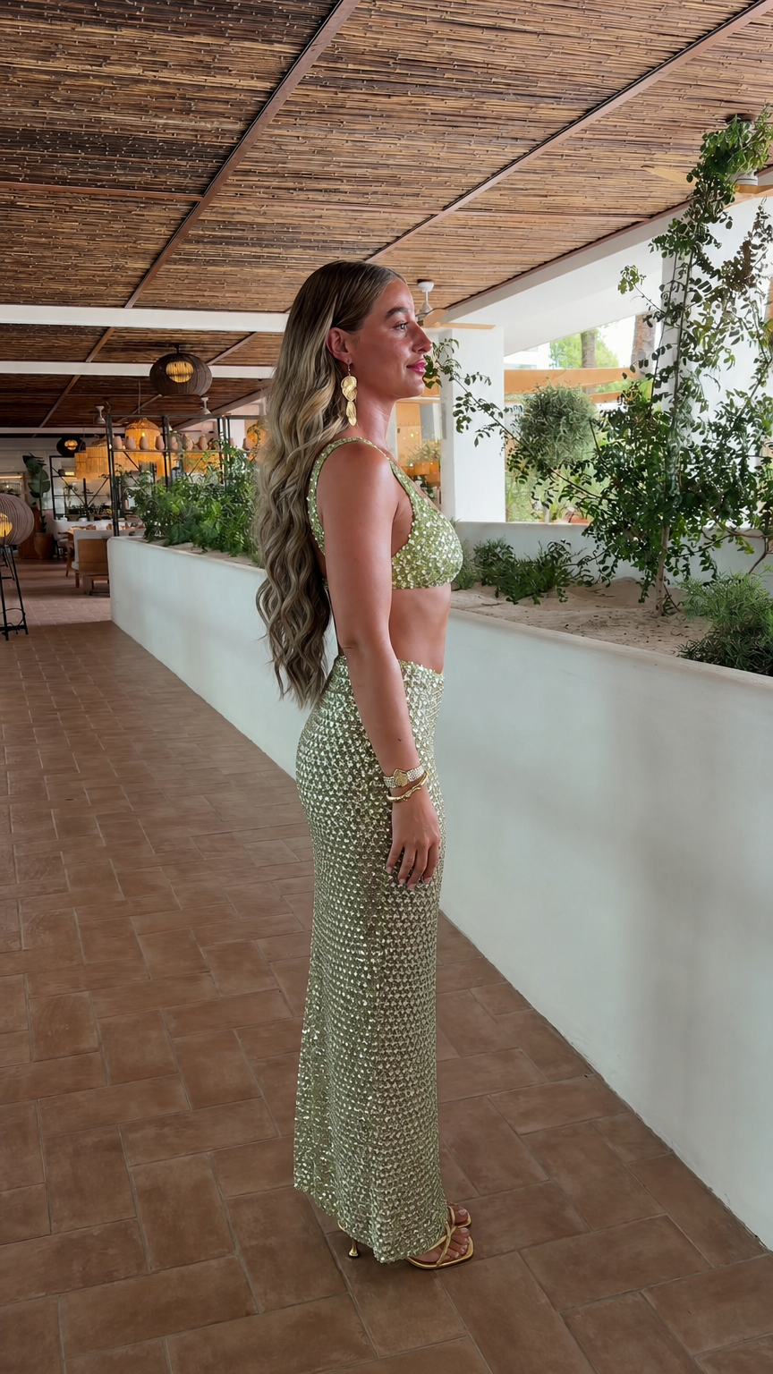 Side profile of model in sage green sequin crop top and maxi skirt
