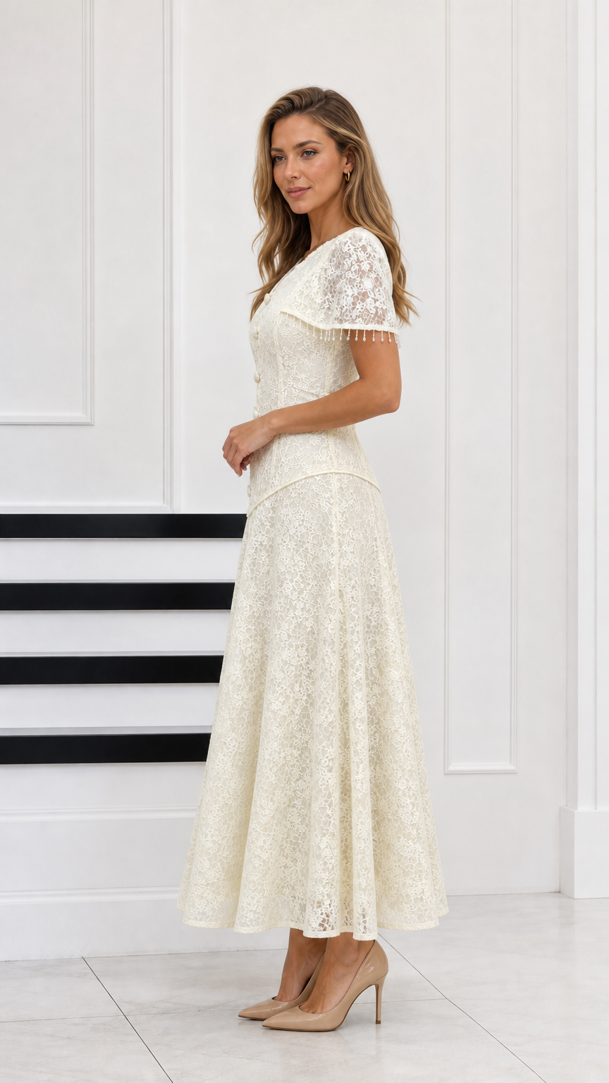 Side profile of woman wearing cream lace evening gown with capelet detail