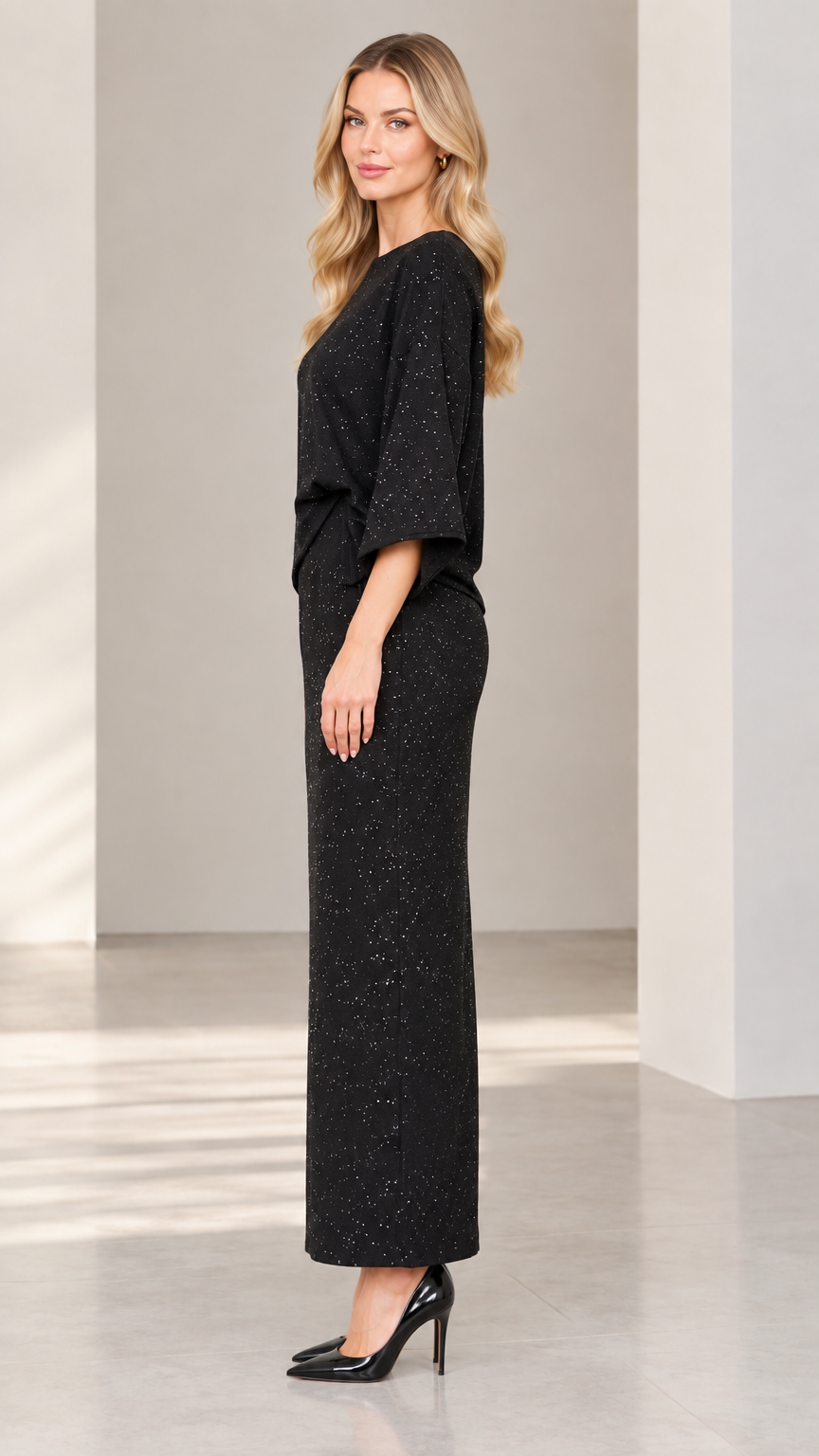Side profile view of woman modeling black glitter two-piece maxi set with high heels
