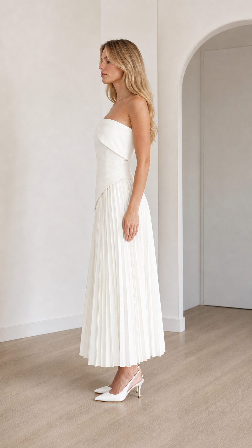 Side view of model in white pleated midi dress