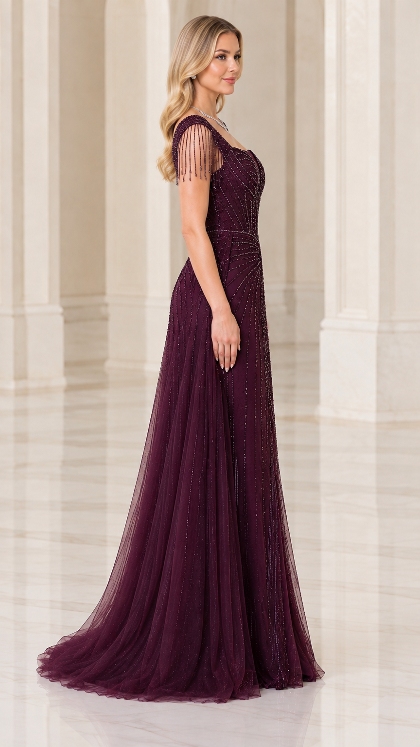 Side profile of burgundy beaded gown showing flowing tulle train and fringe sleeves