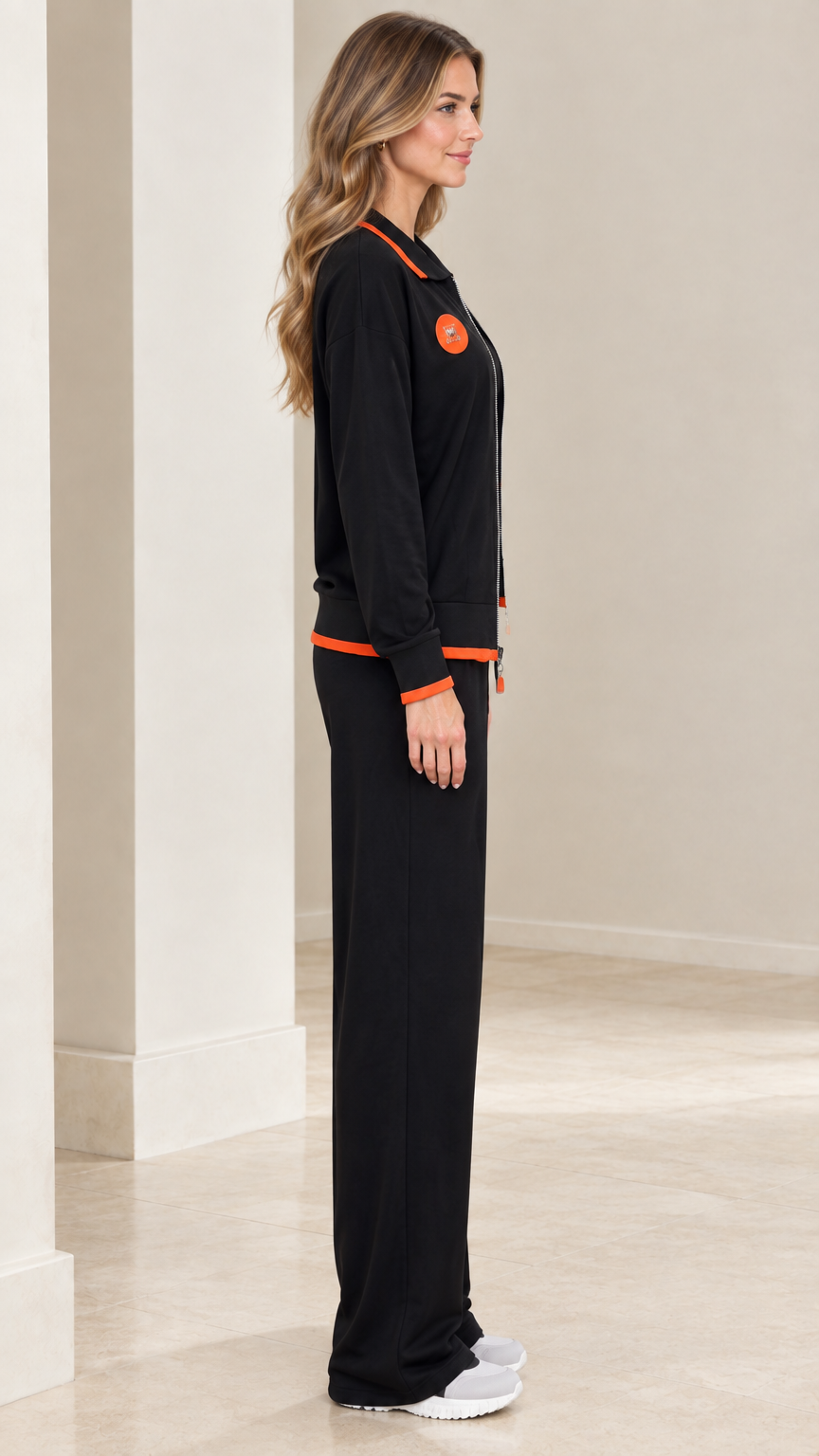 Side profile view of model in black loungewear set with zip jacket and wide-leg pants