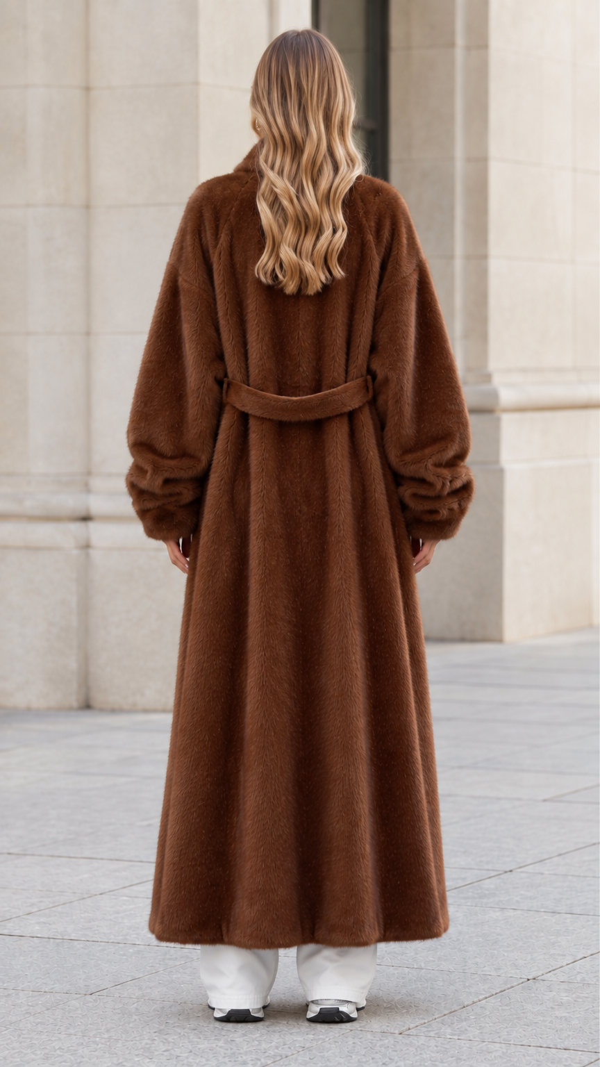 Back view of woman wearing chocolate brown plush coat highlighting the back belt detail