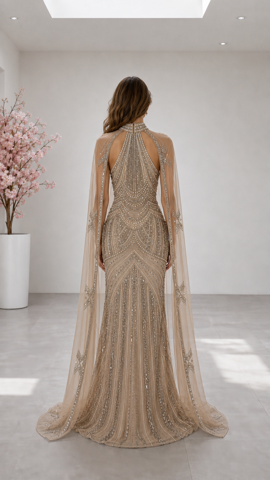 Back view of champagne halter neck gown showing cut-out back and flowing sheer cape