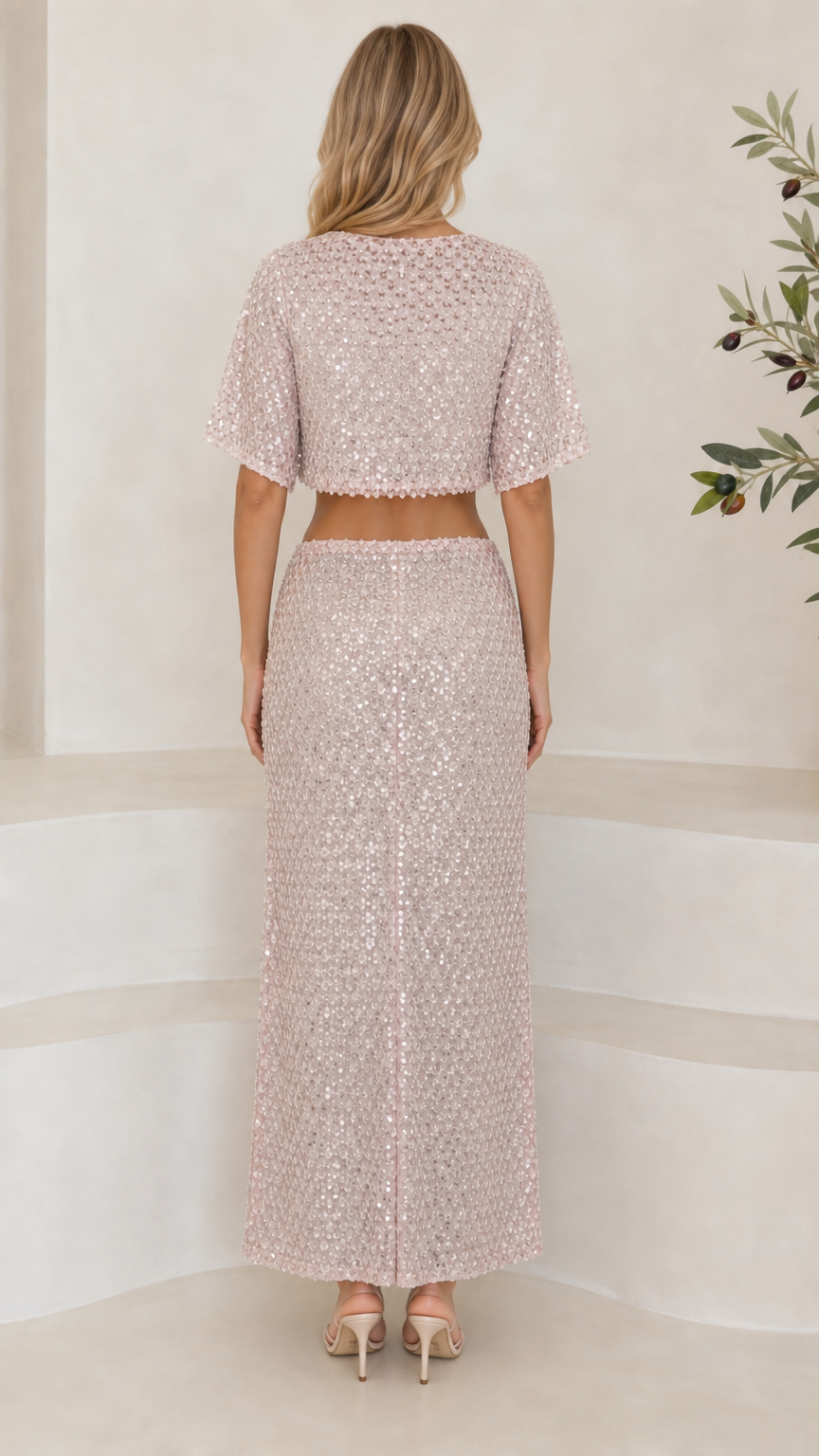Back full-length view of woman in blush pink sequin crop top and column maxi skirt