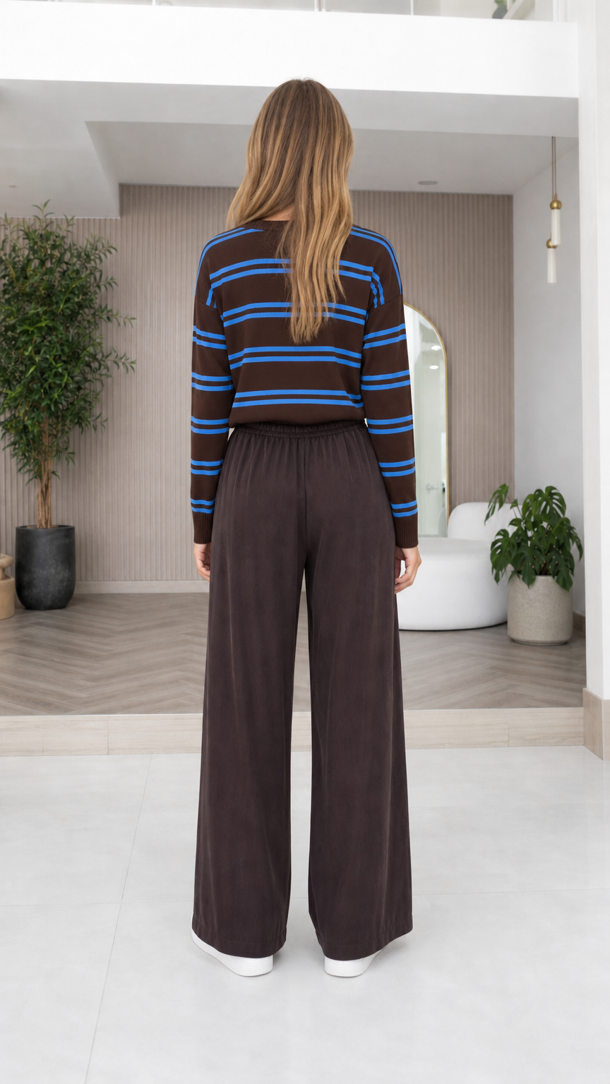 Back view of model wearing brown striped crewneck knit pullover and relaxed wide-leg pants