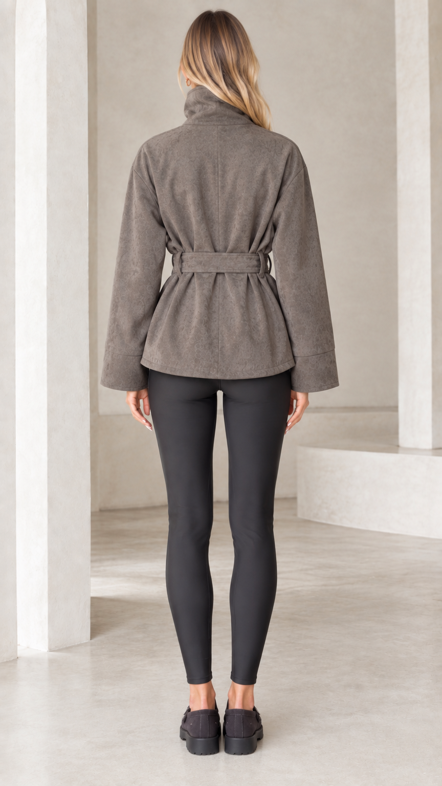 Back view of model wearing taupe belted faux suede jacket with stand collar